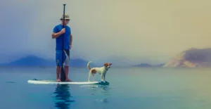 man and dog on the water board
